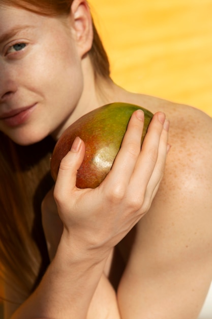 Bezpłatne zdjęcie widok z boku buźka kobieta trzyma mango
