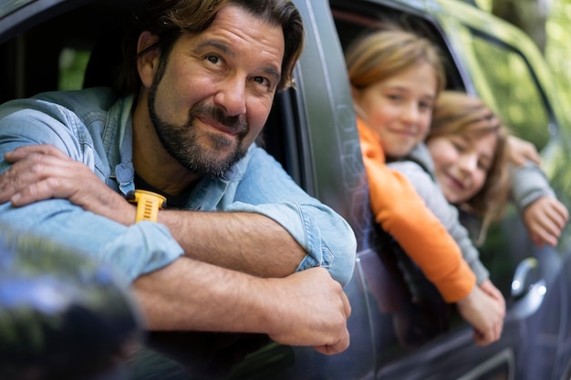 Widok z boku buźki ojca i dzieci w samochodzie