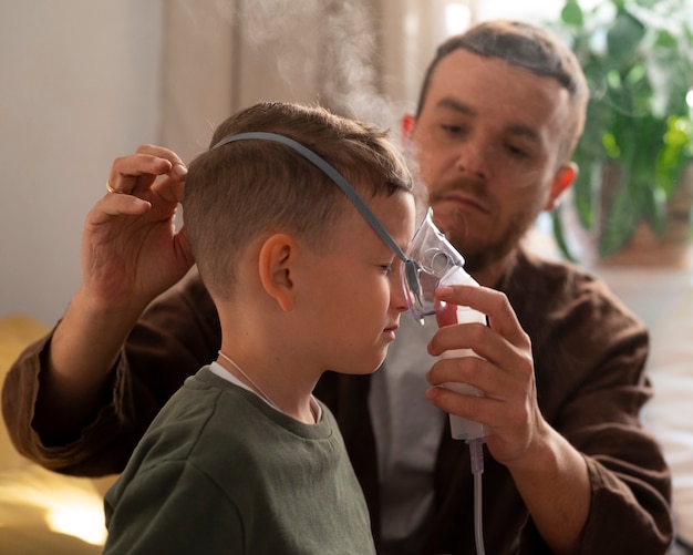 Bezpłatne zdjęcie widok z boku chorego dziecka za pomocą nebulizatora