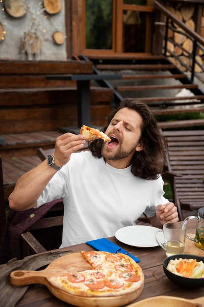 Widok z boku człowieka jedzącego pizzę?