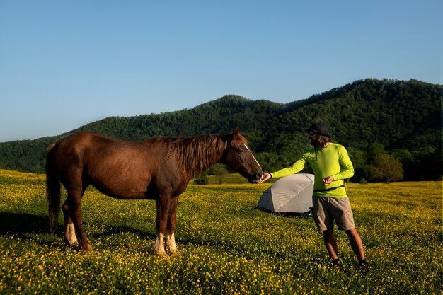 Widok z boku człowieka karmiącego dzikiego konia