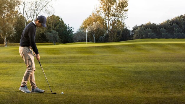 Widok z boku człowieka na trawiastym polu golfowym