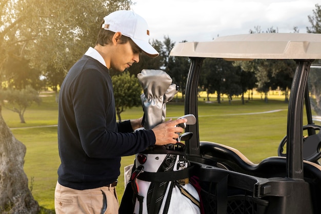 Widok z boku człowieka umieszczanie klubów w wózku golfowym