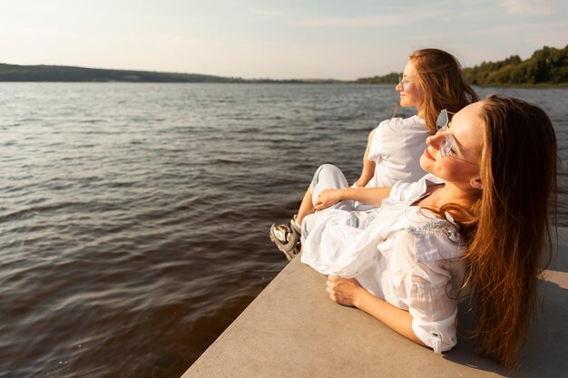 Widok z boku dwóch kobiet podziwiających widok na jezioro
