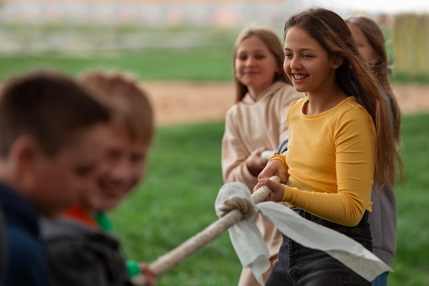 Widok z boku dzieci bawiące się w przeciąganie liny w parku