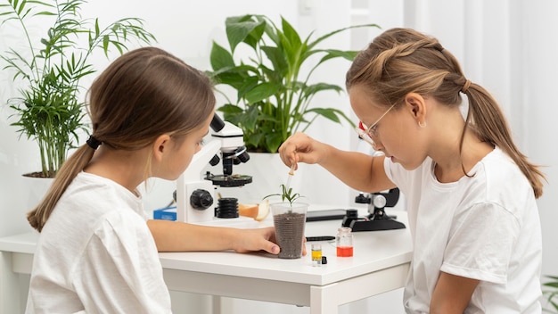 Bezpłatne zdjęcie widok z boku dziewcząt uczących się o nauce z rośliną