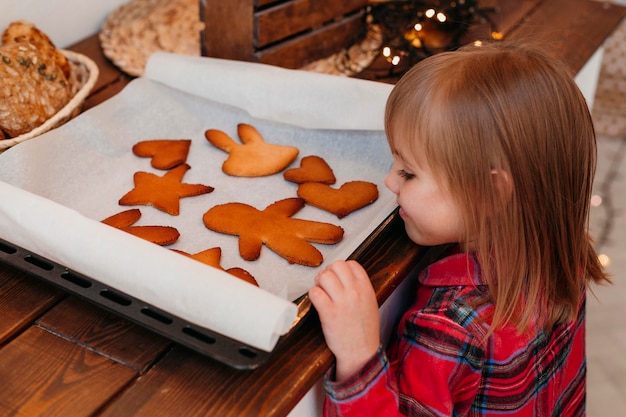 Widok z boku dziewczyna sprawdza pieczone ciasteczka świąteczne