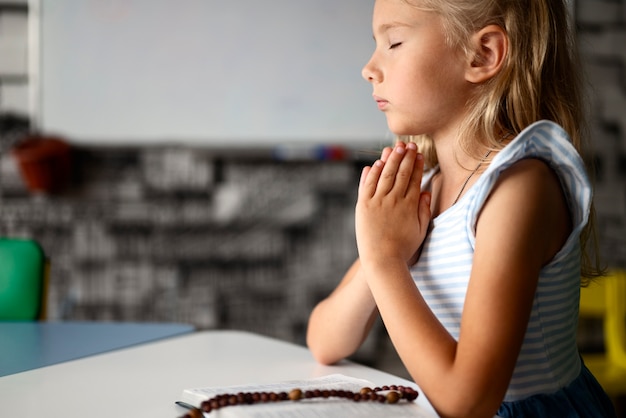 Widok z boku dziewczyny modlącej się w niedzielnej szkole