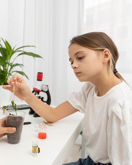 Widok z boku dziewczyny uczącej się nauki z rośliną