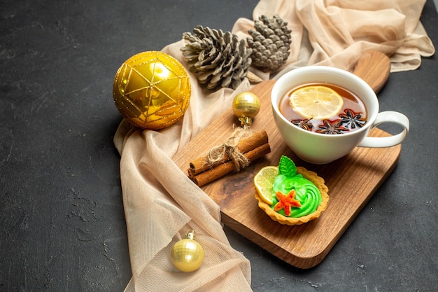 Widok z boku filiżanki czarnej herbaty z cytryną i limonkami cynamonowymi akcesoriami do dekoracji nowego roku na drewnianej desce do krojenia