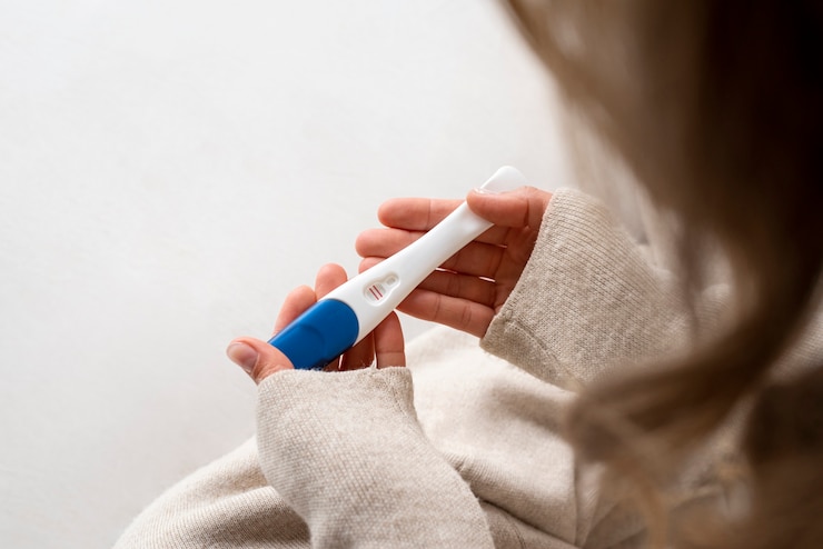 Bezpłatny plik Zdjęcie widok z boku kobieta trzymająca pozytywny test ciążowy