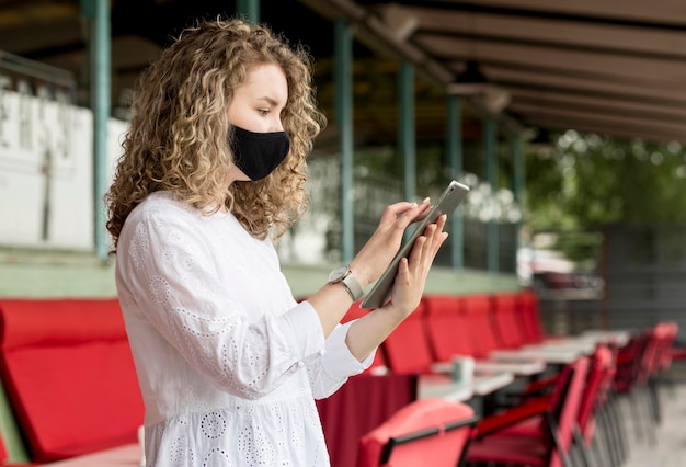 Widok z boku kobieta z maską za pomocą tabletu