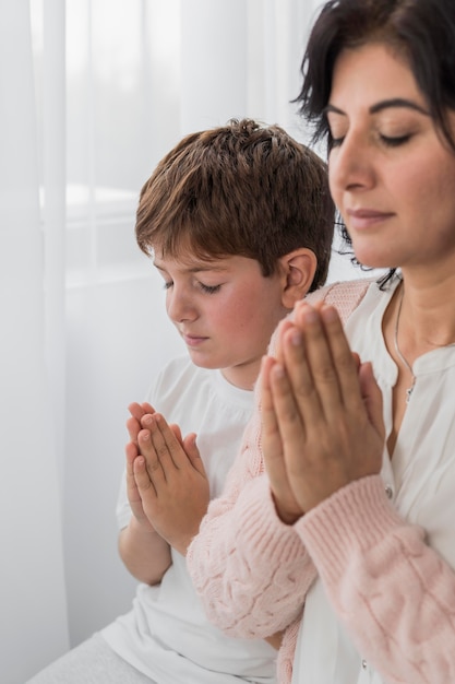 Bezpłatne zdjęcie widok z boku kobiety modlącej się z dzieckiem