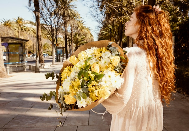 Widok z boku kobiety na zewnątrz z bukietem wiosennych kwiatów