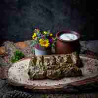 Bezpłatne zdjęcie widok z boku liście winogron dolma faszerowane mięsem i ryżem z sosem śmietanowym na ciemnym drewnianym stole. tradycyjna kuchnia wschodnioeuropejska i azjatycka