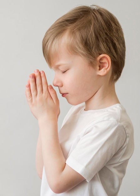 Widok z boku małego chłopca modlącego się