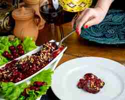 Bezpłatne zdjęcie widok z boku marynowanej sałatki owocowej ręką orzechów włoskich, zbierając jedzenie z talerza sałatkowego