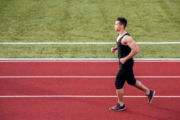 Widok z boku męskiej sprinter biegacza na torze wyścigowym