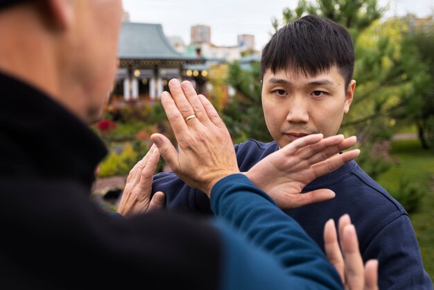 Widok z boku mężczyzn ćwiczących tai chi na zewnątrz