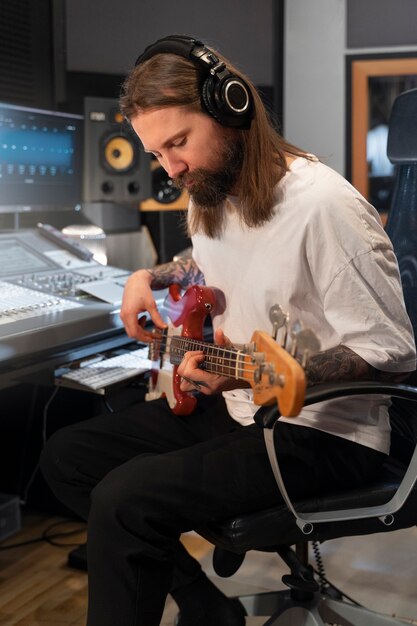 Widok z boku mężczyzna grający na gitarze w studio