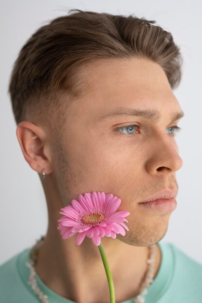 Widok z boku mężczyzna pozuje z różowym kwiatem