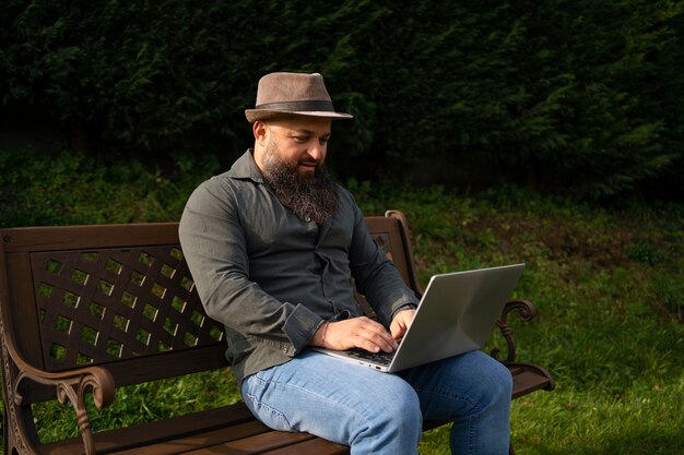 Widok z boku mężczyzna z laptopem na zewnątrz