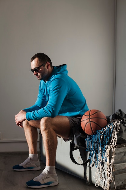 Widok z boku mężczyzny w bluzę i okulary z koszykówką obok niego