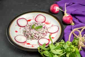 Bezpłatne zdjęcie widok z boku na apetyczny talerz z rzodkiewką i ziołami w sosie oraz fioletowy obrus