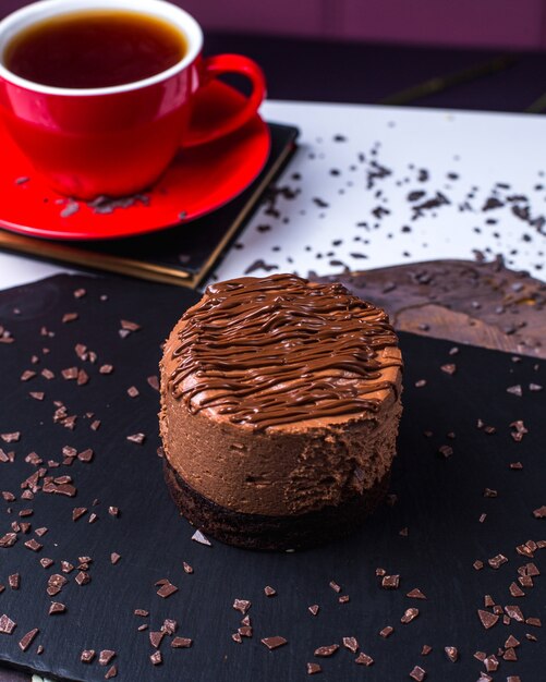 Widok z boku na ciasto czekoladowe podawane z herbatą na czarnej desce