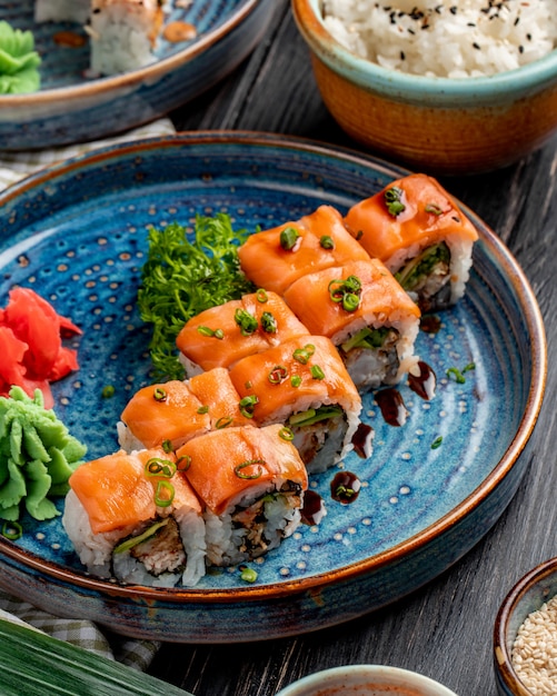 Bezpłatne zdjęcie widok z boku na rolki sushi z awokado z łososia i kremowym serem na talerzu z imbirem i wasabi