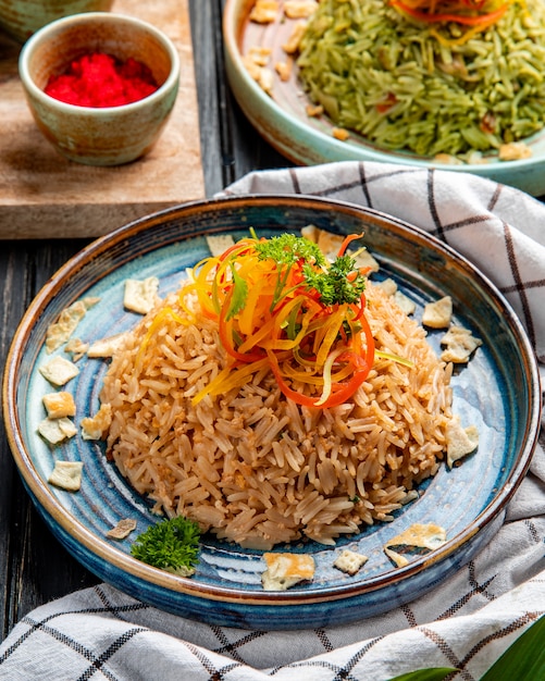 Widok z boku na smażony ryż japoński z warzywami w sosie sojowym na talerzu na drewnie