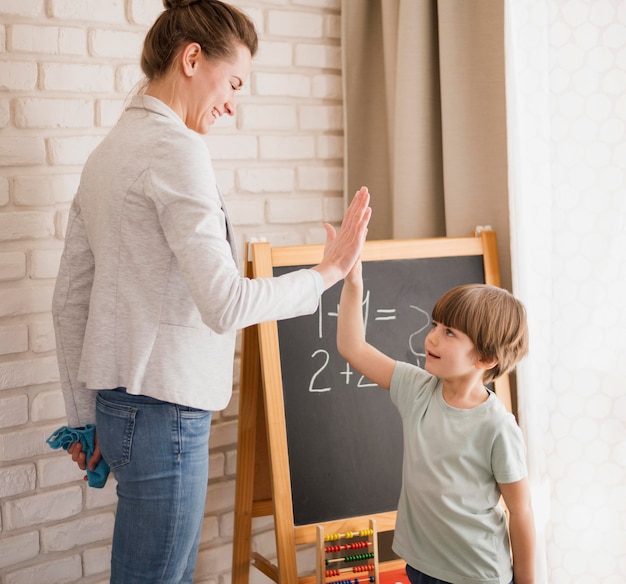 Widok z boku opiekuna wysoko fiving dziecko w domu