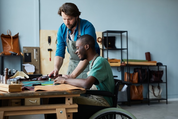 Widok z boku portret młodego mężczyzny na wózku inwalidzkim, uczącego się rzemiosła rymarskiego w warsztacie rymarskim...
