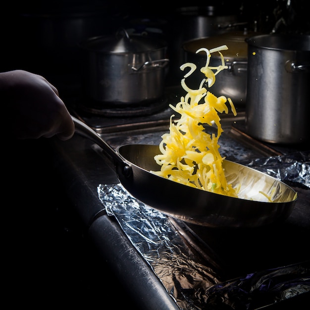 Bezpłatne zdjęcie widok z boku smażenia cebuli z patelni i ludzką ręką w piecu