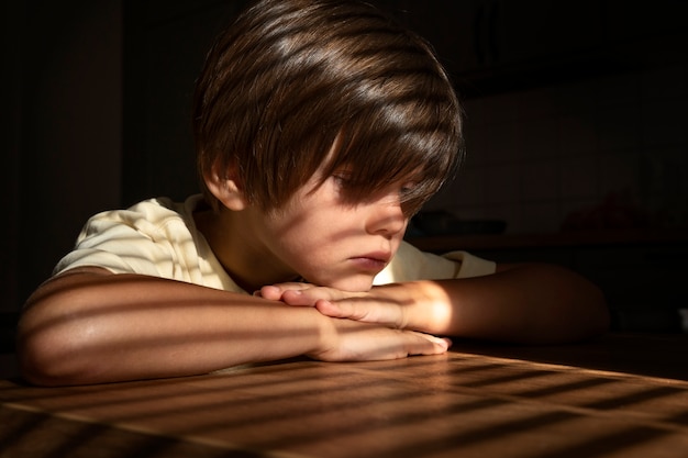 Widok z boku smutny chłopiec siedzący w pomieszczeniu
