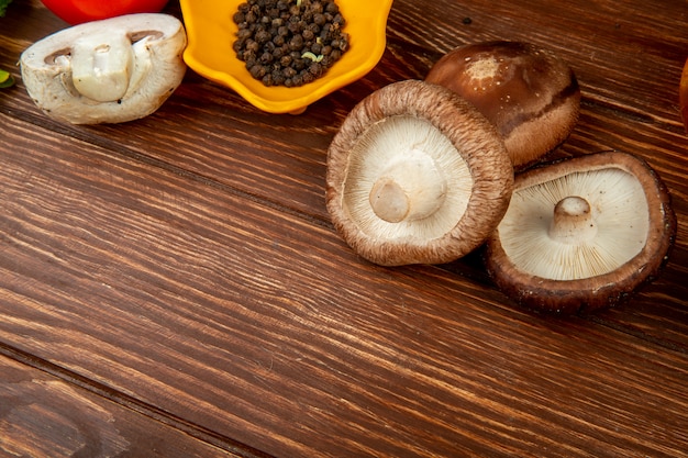 Widok z boku świeżych grzybów i czarnego pieprzu na rustykalnym drewnie z miejsca na kopię
