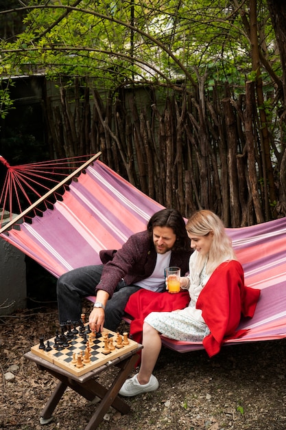 Bezpłatne zdjęcie widok z boku szczęśliwi ludzie grający w szachy w hamaku