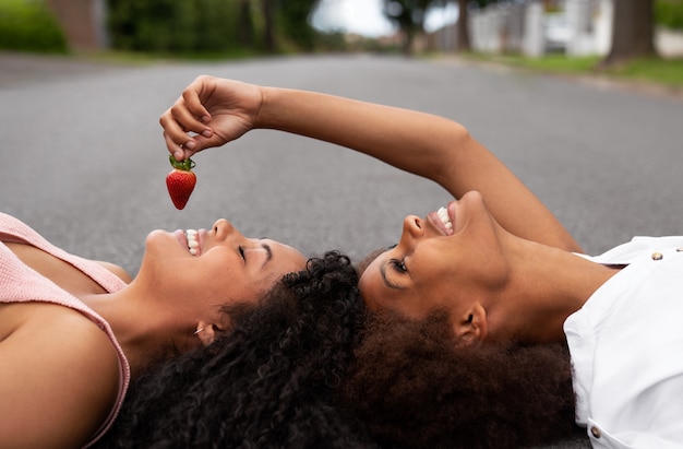 Bezpłatne zdjęcie widok z boku uśmiechniętych przyjaciół jedzących truskawki