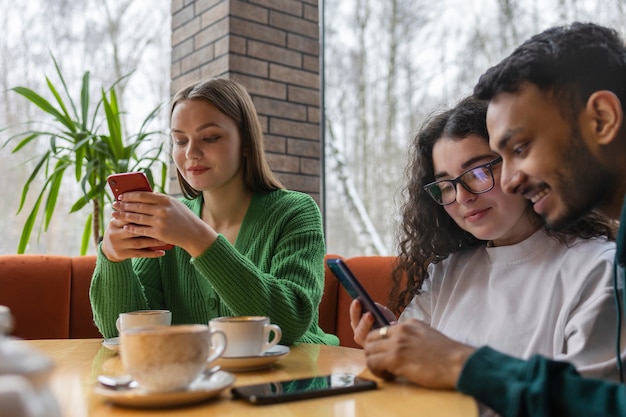 Widok z boku uśmiechniętych przyjaciół ze smartfonem