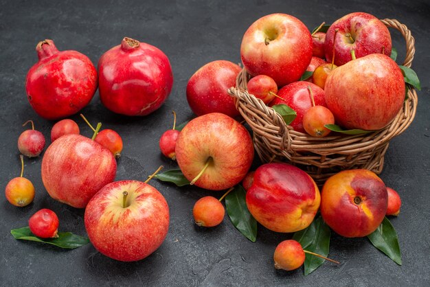 Widok z boku z bliska owoce drewniany kosz jabłek wiśnie pozostawia granaty nektaryny