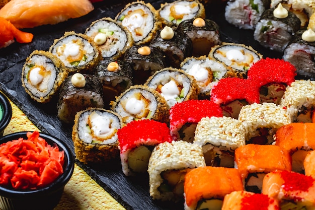 Widok z boku zestaw sushi Alaska Roll Chuckien Hot Roll California z mięsem kraba i kawiorem tobiko Maki i Filadelfią z twarogiem na tacy