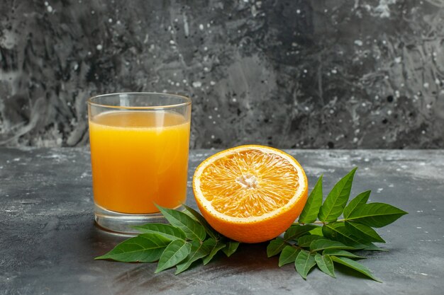 Widok z boku źródła witaminy wyciąć świeże pomarańcze i sok z liśćmi na szarym tle