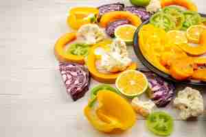 Bezpłatne zdjęcie widok z dołu pokrojone warzywa i owoce papryka dynia persimmon czerwona kapusta zielone pomidory na czarnym talerzu na drewnianym stole