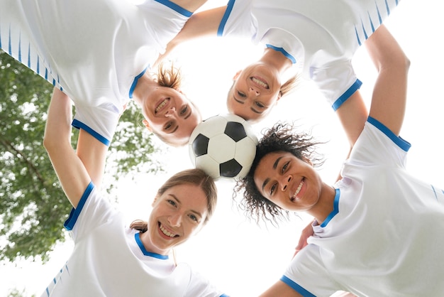 Widok z dołu uśmiechnięte kobiety trzymające piłkę
