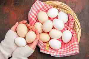 Bezpłatne zdjęcie widok z góry białe jaja kurze wewnątrz kosza z ręcznikiem na ciemnym stole jedzenie surowe gospodarstwo śniadanie kolorowy posiłek fotograficzny