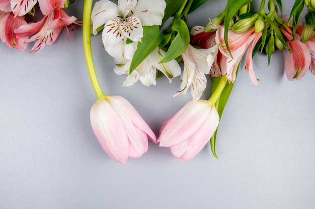 Bezpłatne zdjęcie widok z góry białych i różowych kolorów alstremeria kwiaty z różowe tulipany na białym stole
