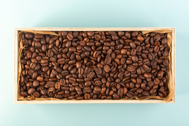 Widok z góry brązowe ziarna kawy w pudełku na niebieskiej ścianie kubek kawy zdjęcie nasion napoju