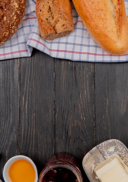 widok z góry chleba jako zaszczepione wietnamskie czarne bagietki na tkaninie z masłem i dżemem na drewnianym stole z miejsca kopiowania