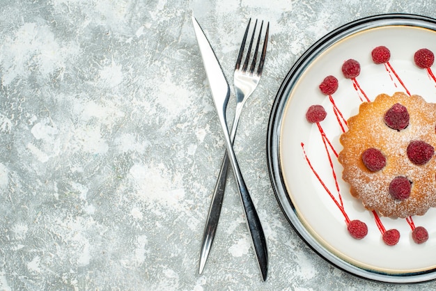 Widok z góry ciasto jagodowe na białym owalnym talerzu widelec i nóż obiadowy na szarej powierzchni wolnej przestrzeni
