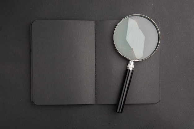 Widok z góry czarne szkło powiększające notebooka na ciemnym stole